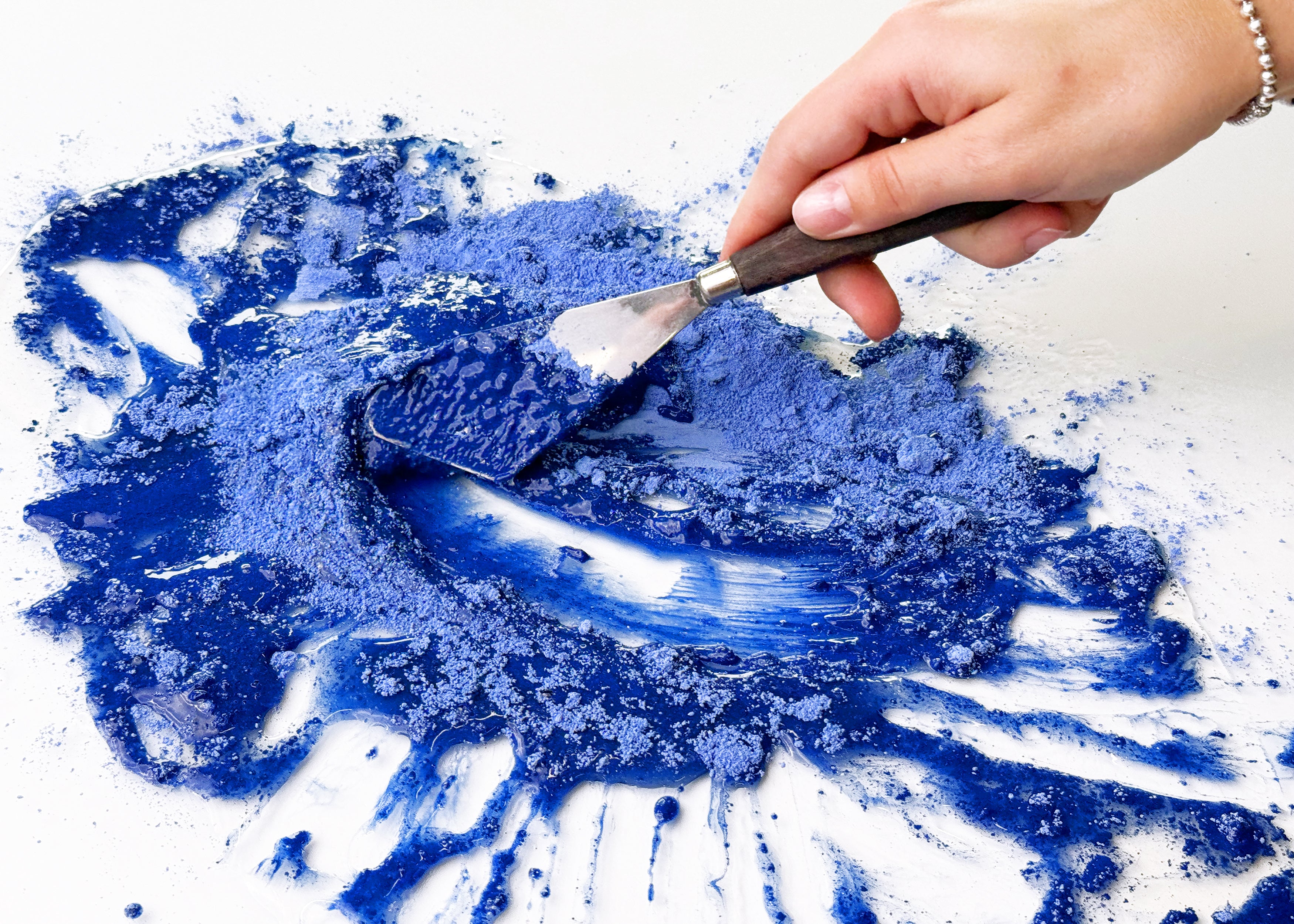 Hand mulling natural blue pigment with binder on glass slab to create A. Gallo handmade watercolors