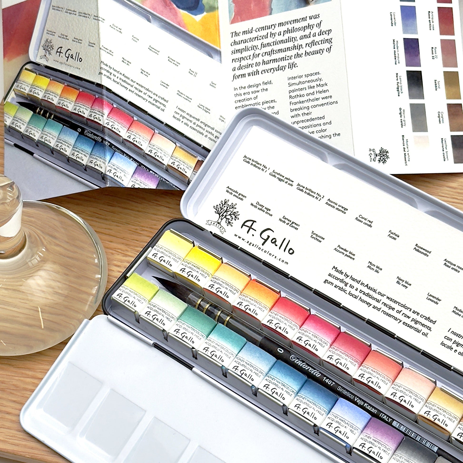 A. Gallo watercolor paint sets on a wooden surface with a color swatch in the background.