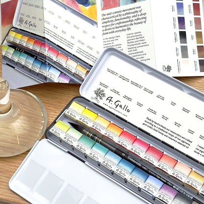 A. Gallo watercolor paint sets on a wooden surface with a color swatch in the background.
