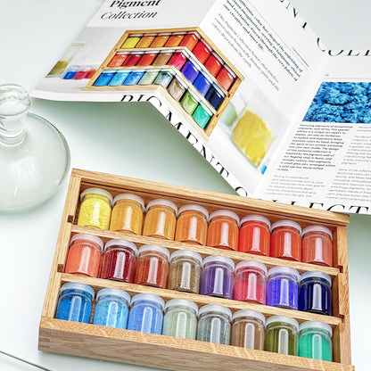 Set of colorful paint jars in a wooden box with an open magazine in the background.